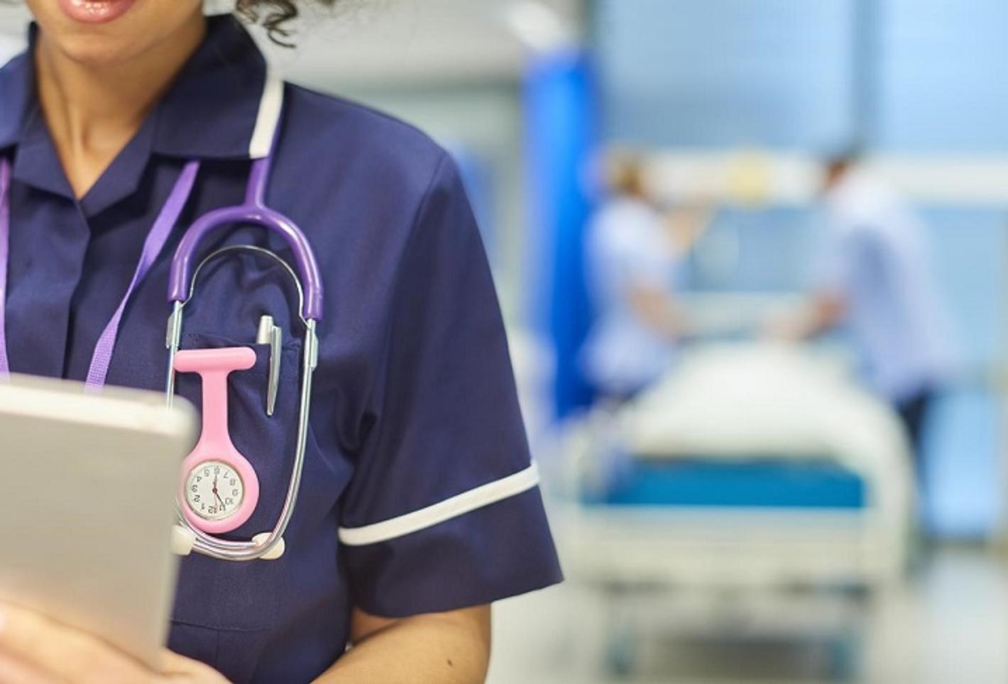 A healthcare professional holding a digital device in a hospital