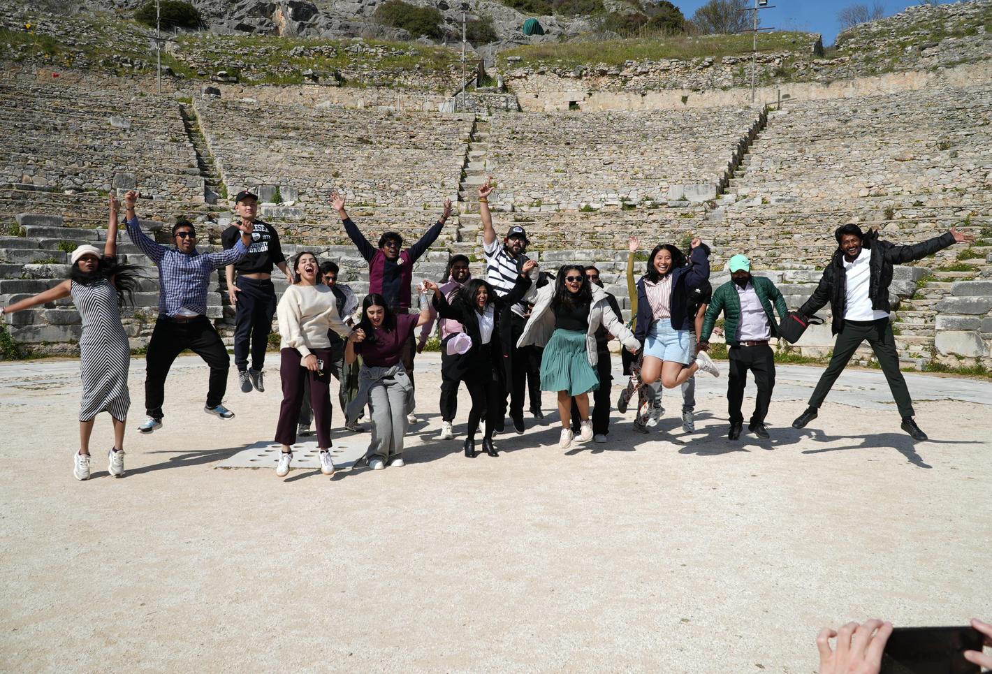 Students jump in the air at an ampitheatre