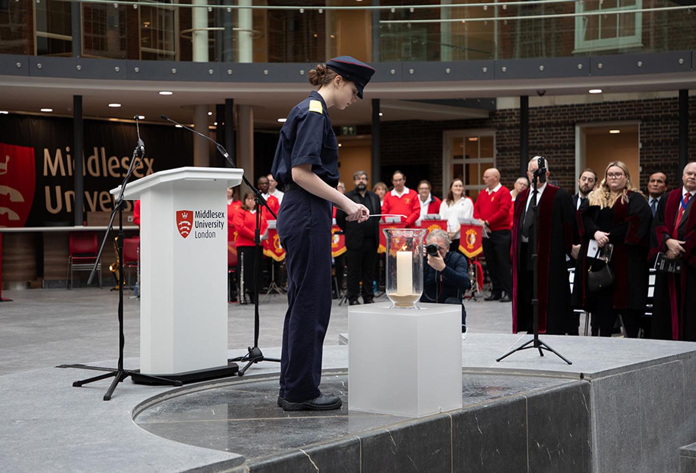 A cadet lights a candle at a memorial event