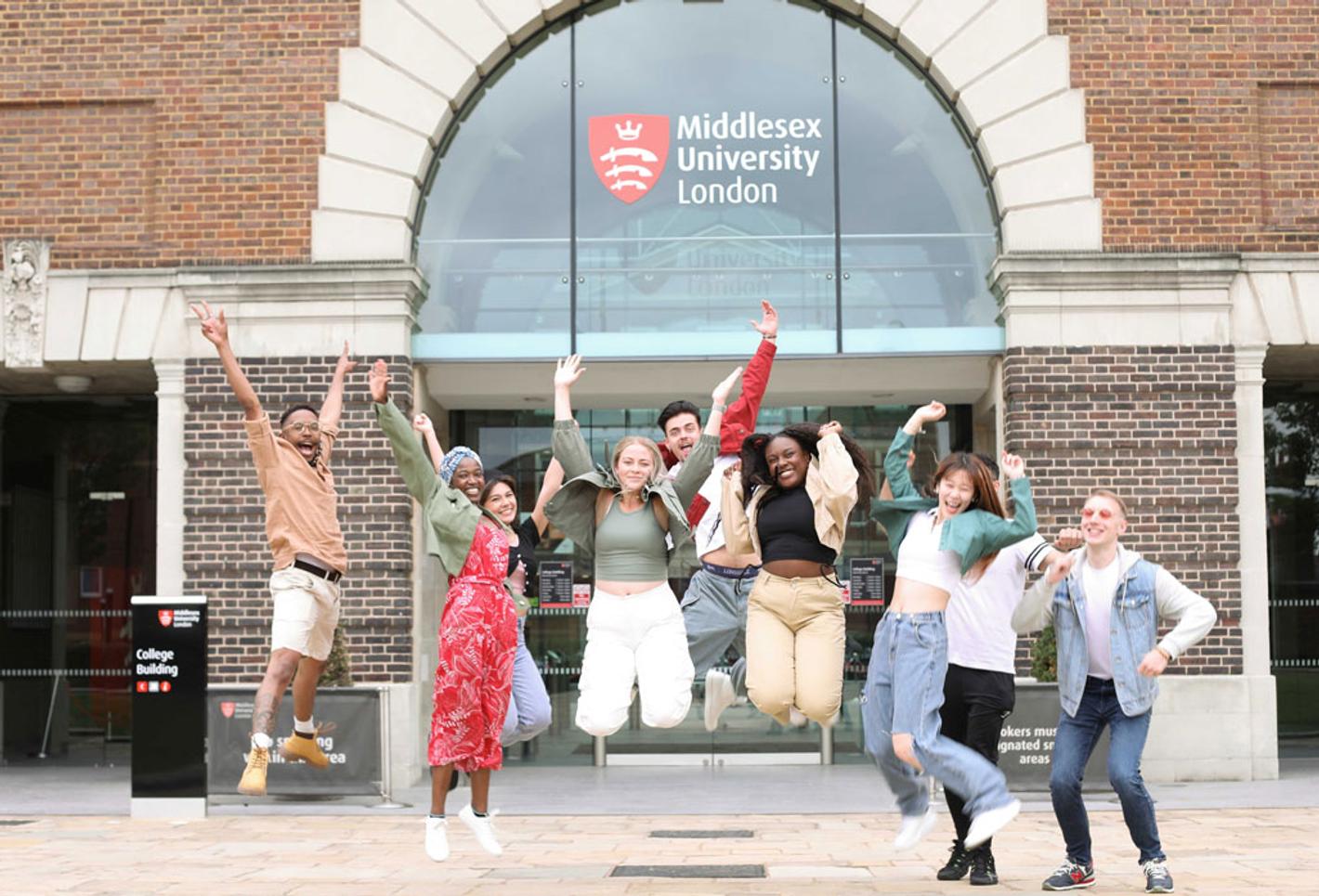 Group of students jumping with joy in front of Middlesex University building