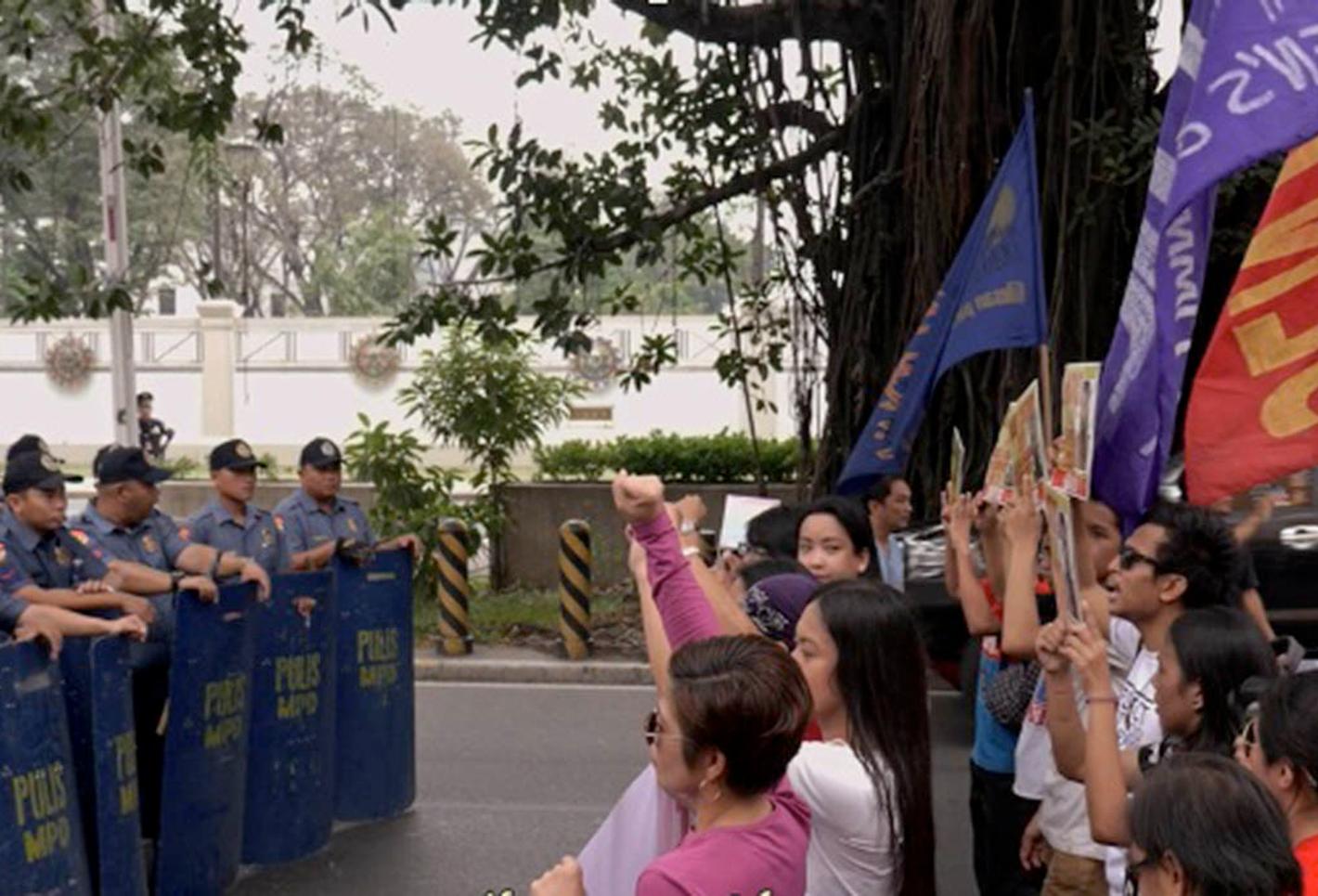 Crowds waving banners stand across from police