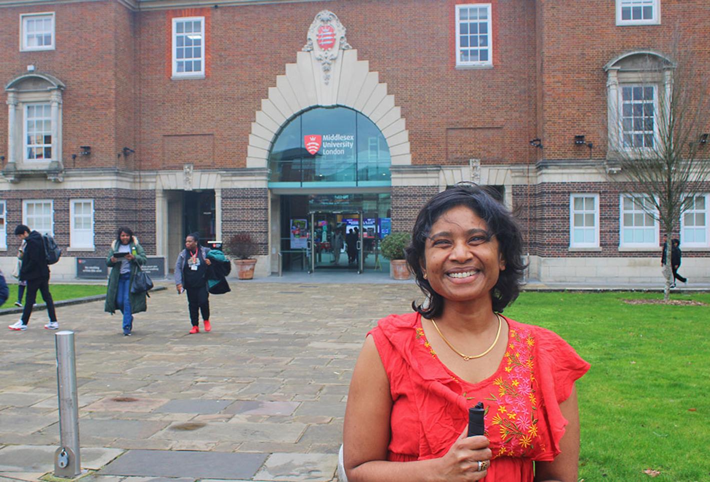 Woman in red top stands outside university