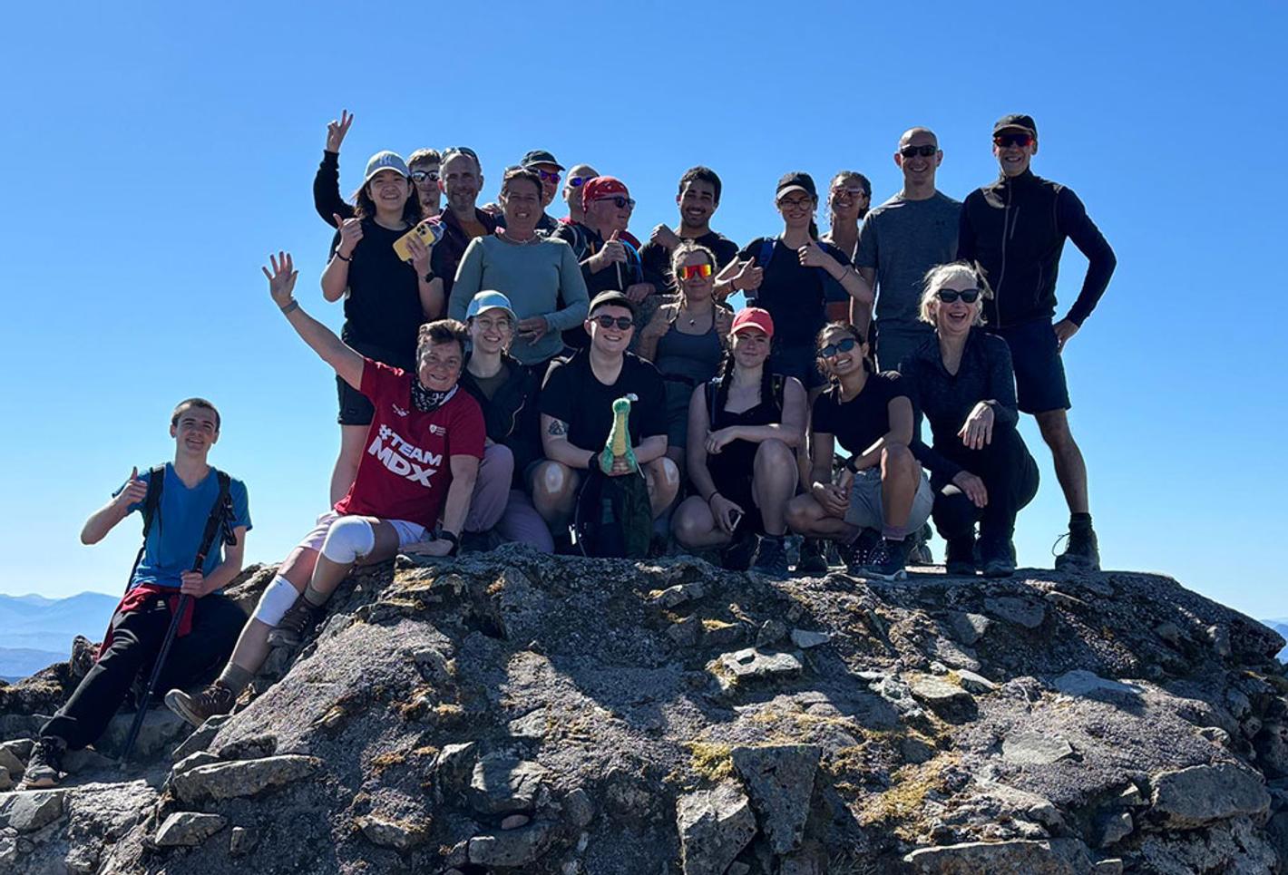 Students and staff celebrate on top of a mountain