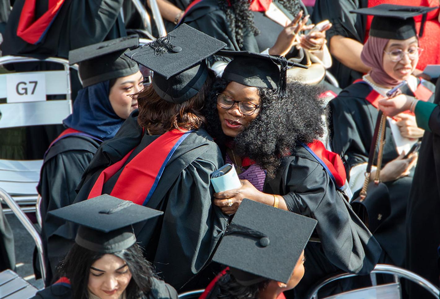 Two students hug during a graduation ceremony