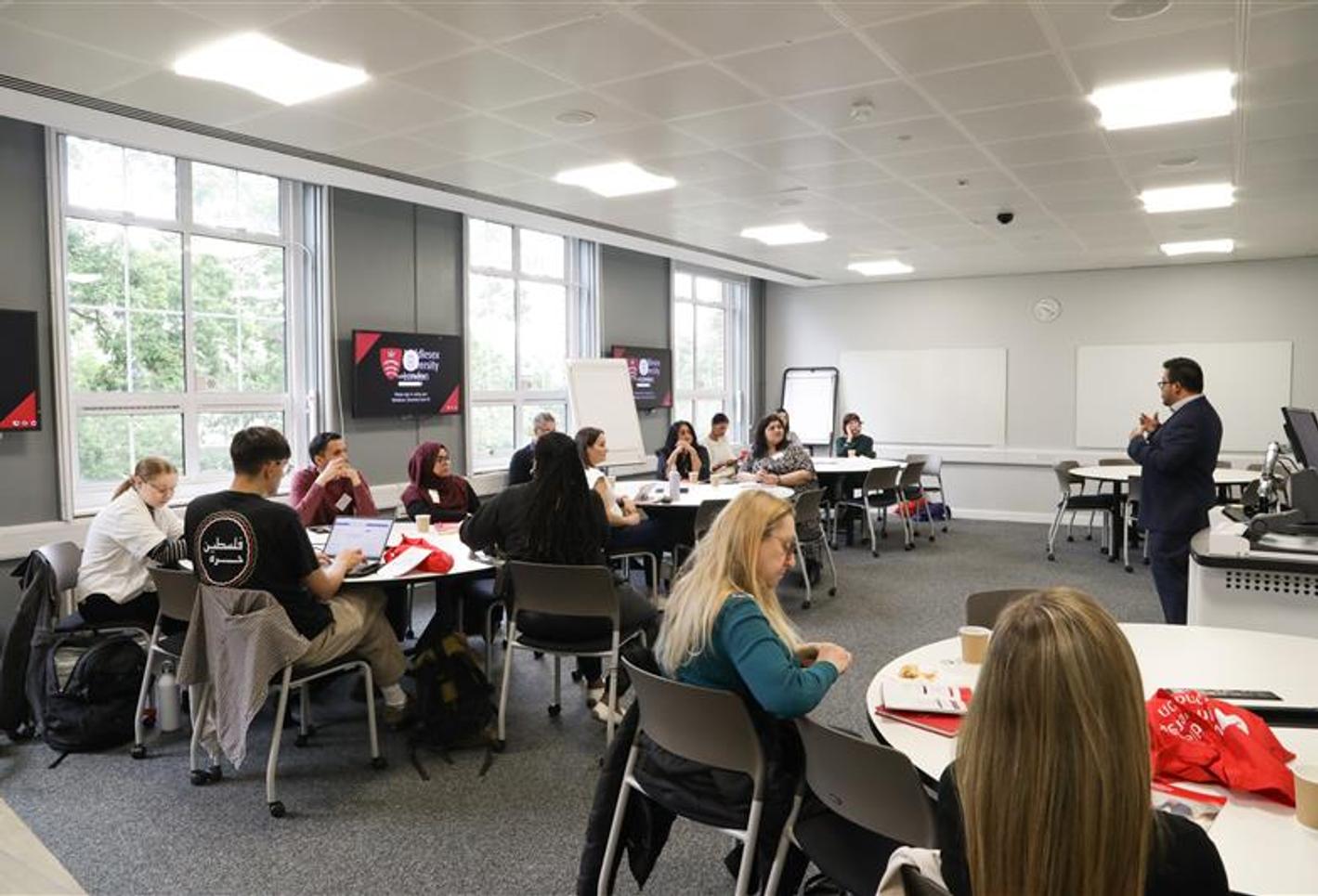 Teachers at the careers convention sitting down at tables talking.