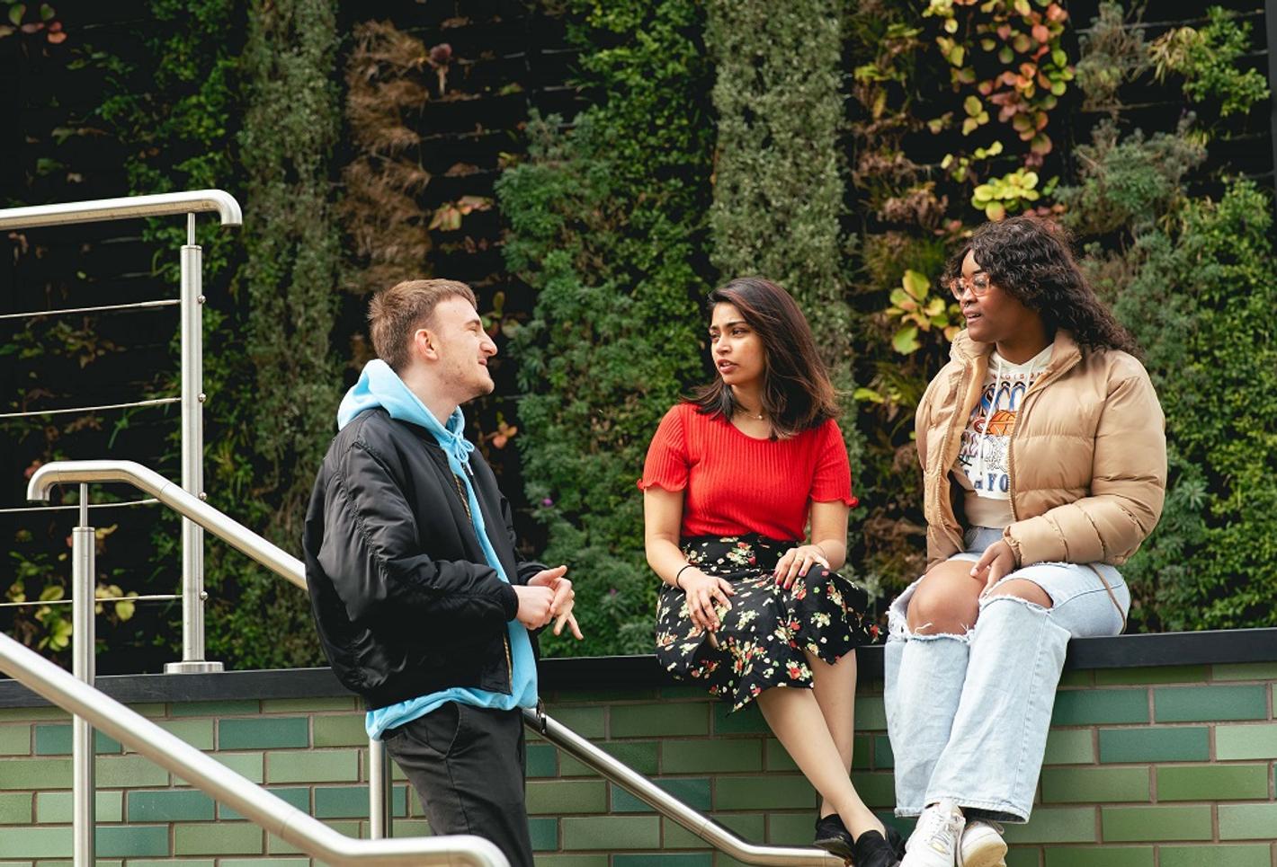 3 people posing in front of a green wall