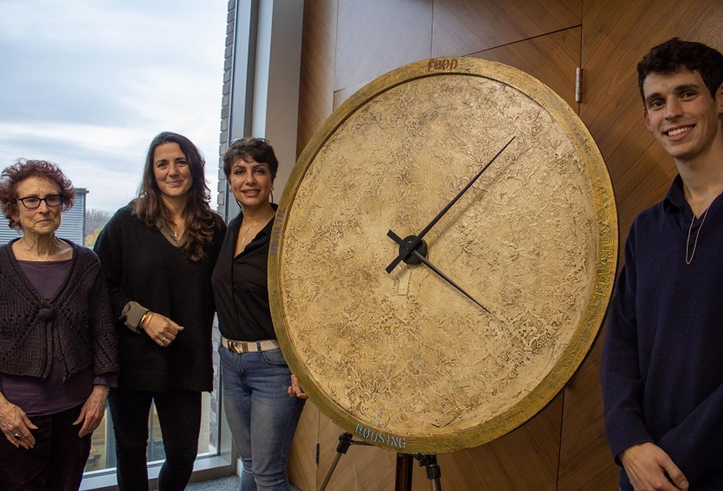 Four individuals standing beside a towering clock, looking up in awe.