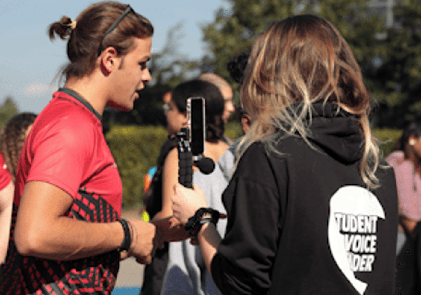 A man in a red shirt engaged in sports or building his reporting portfolio.