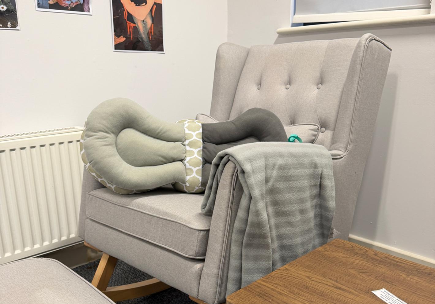 A grey easy chair with a large grey cushion
