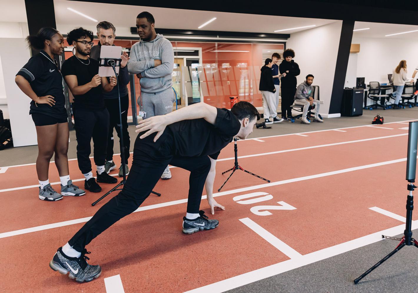 Sport and exercise students analyse an athlete's movement using digital equipment in a performance laboratory.
