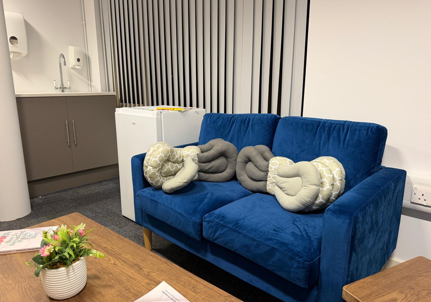 A blue couch in a room with large grey cushions
