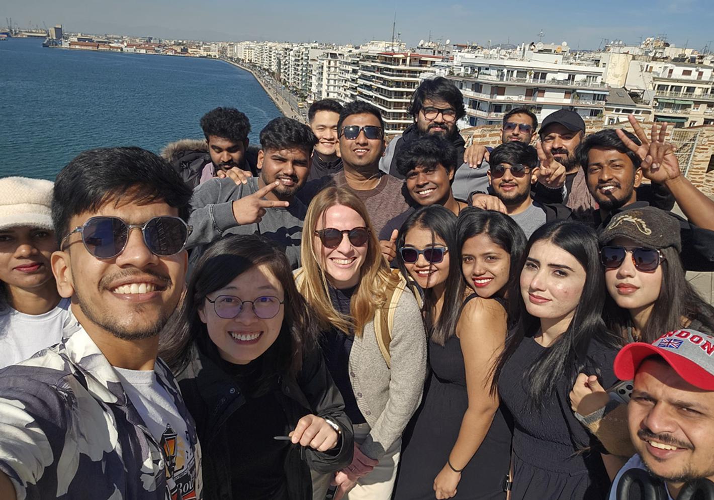 A group of people posing for a photo on top of the White Tower of Thessaloniki, Greece