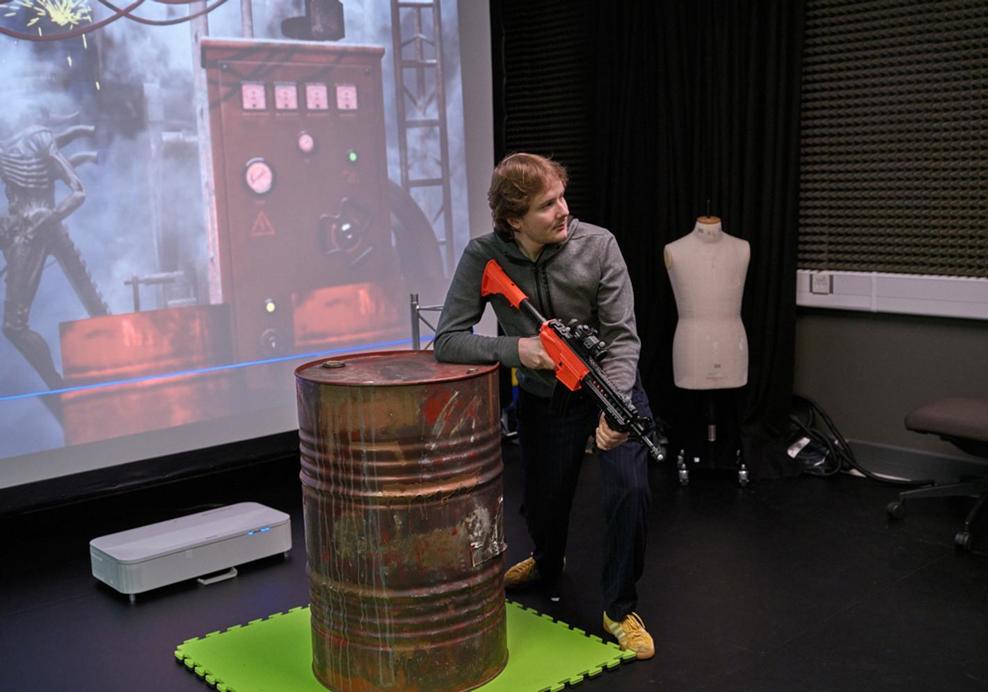 A student in a VFX studio with a video game rifle