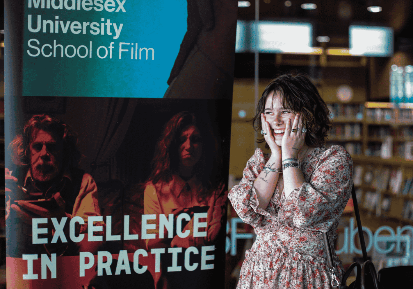 A student standing in front of a banner School of Film