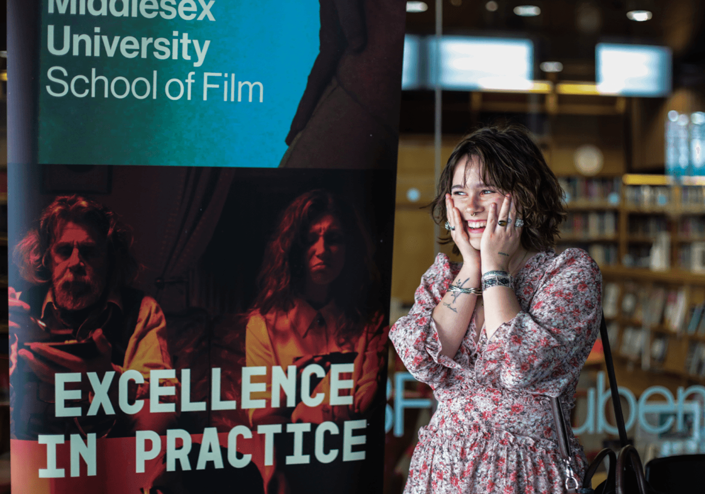 A student standing in front of a banner School of Film