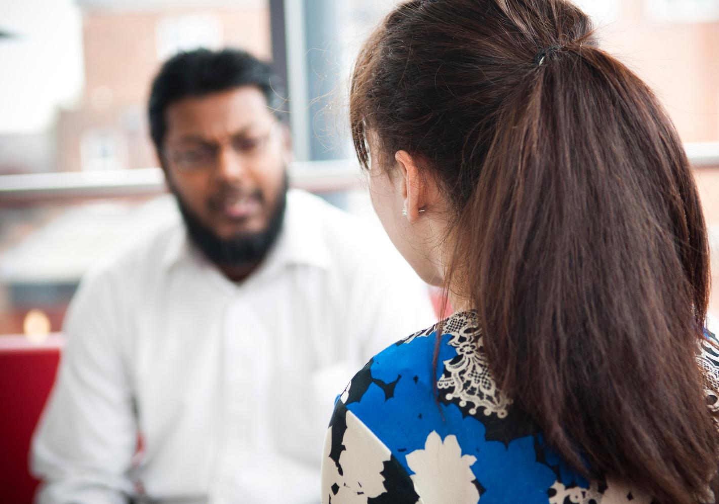 close up of back of patients head as they talk to therapist in background