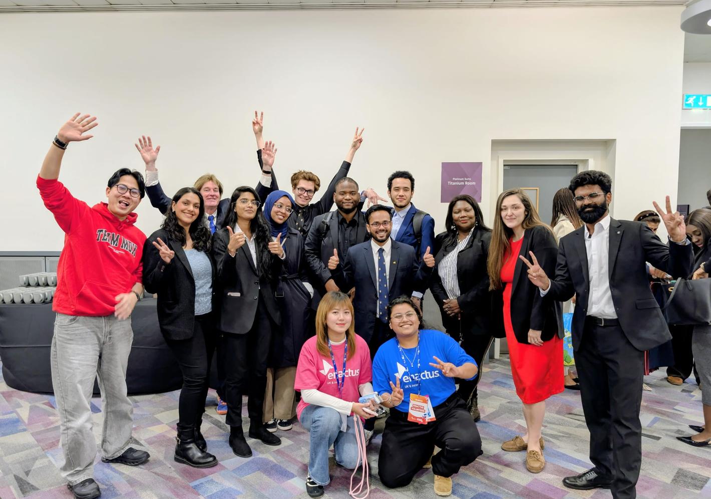 Group of 91��ɫ University students smiling and raising their hands at an Enactus event.