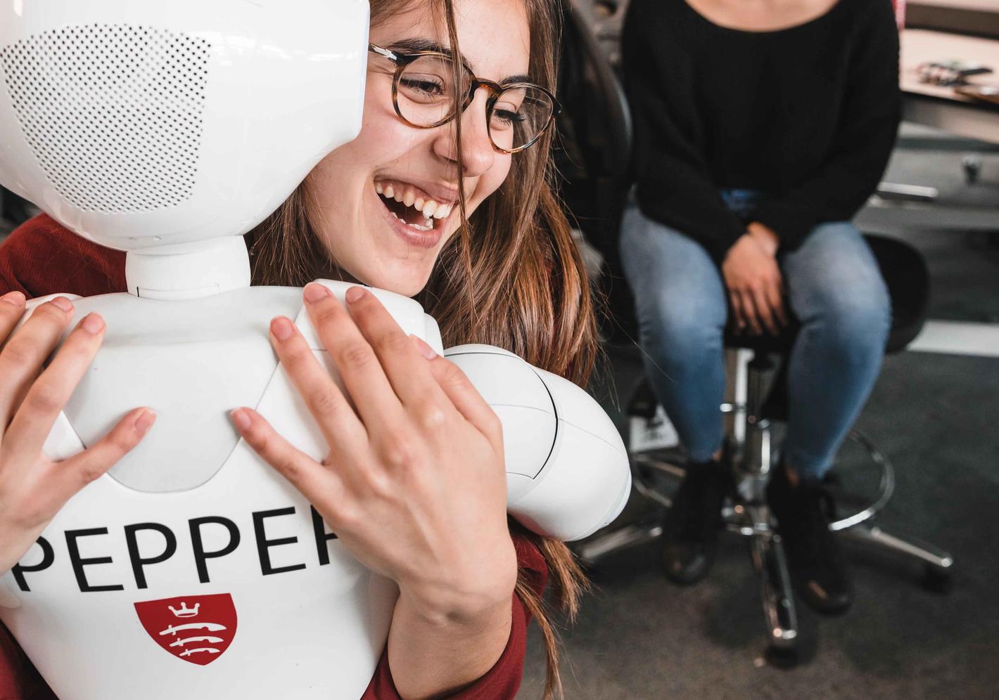 A student hugging a robot named Pepper