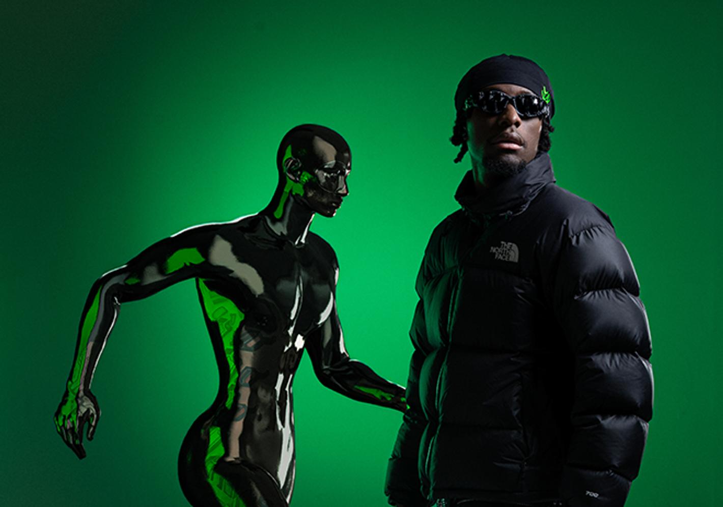 Student posing alongside a robot, with a green screen background
