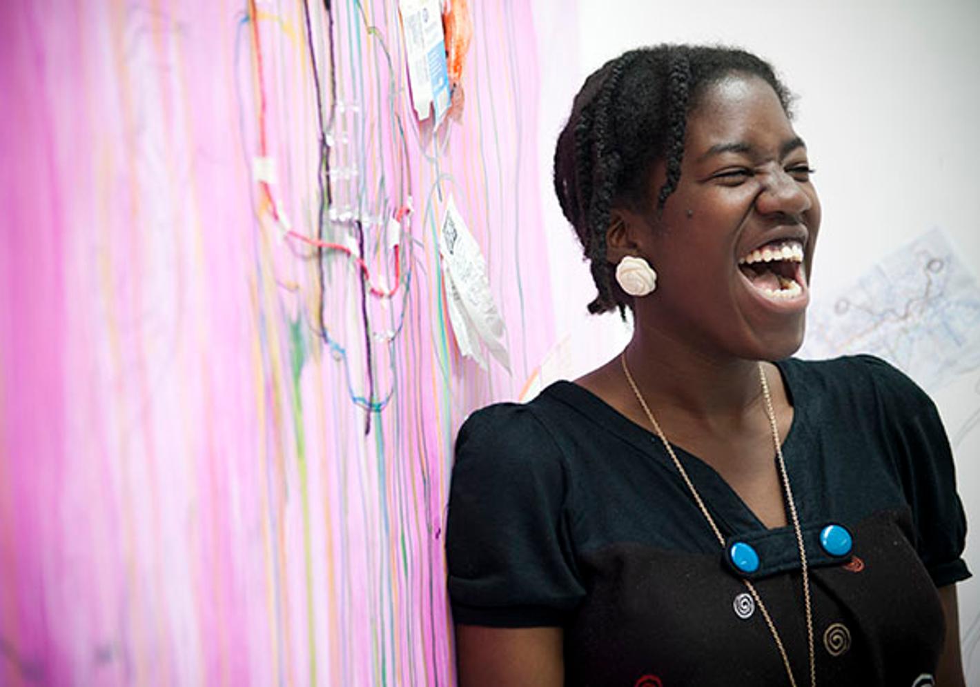 student smiling in front of pink artwork