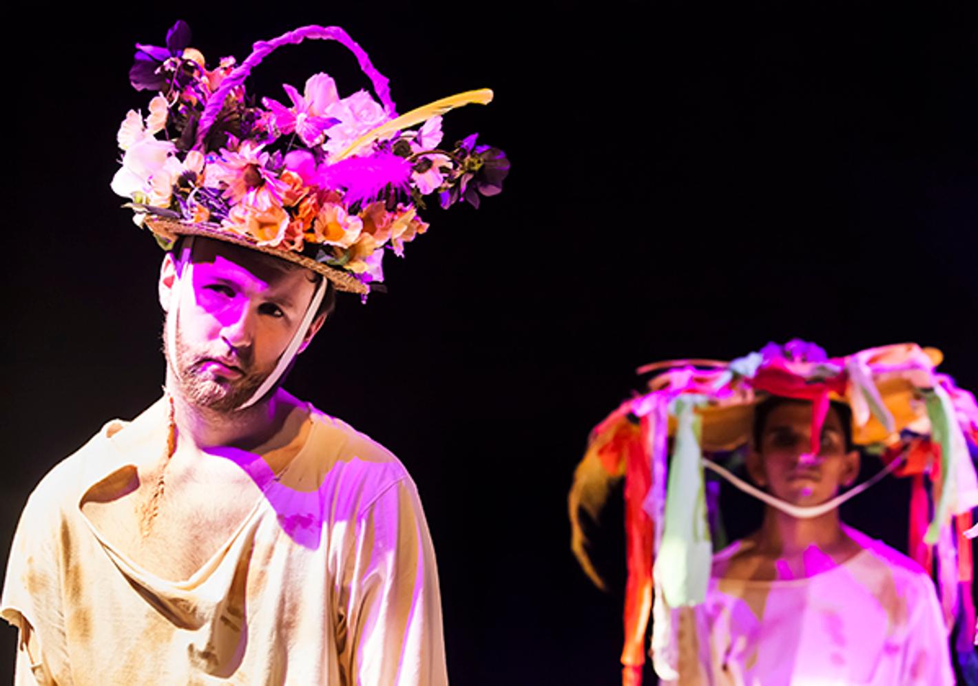 two students on stage wearing elaborate floral headresses