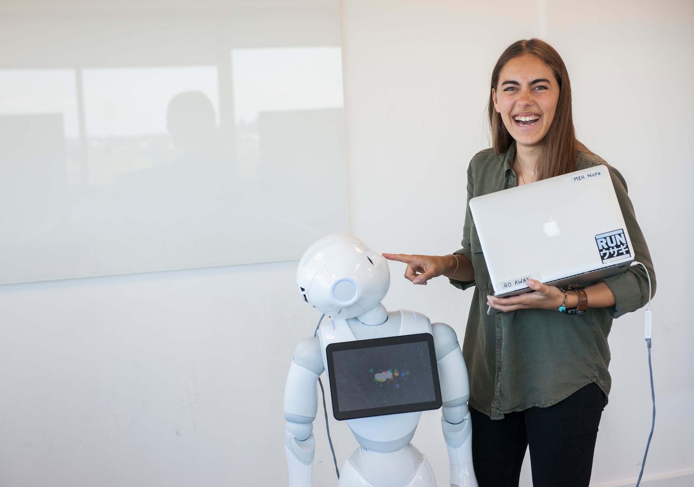 A student smiling next to a large robot