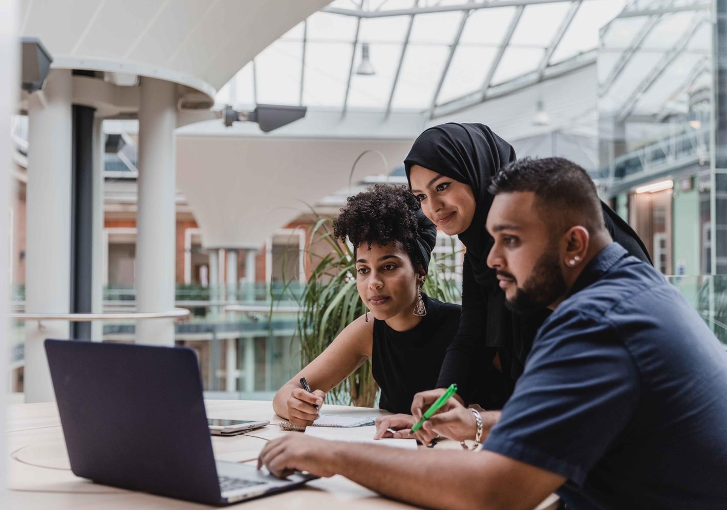 Business management students working on a computer at the quad