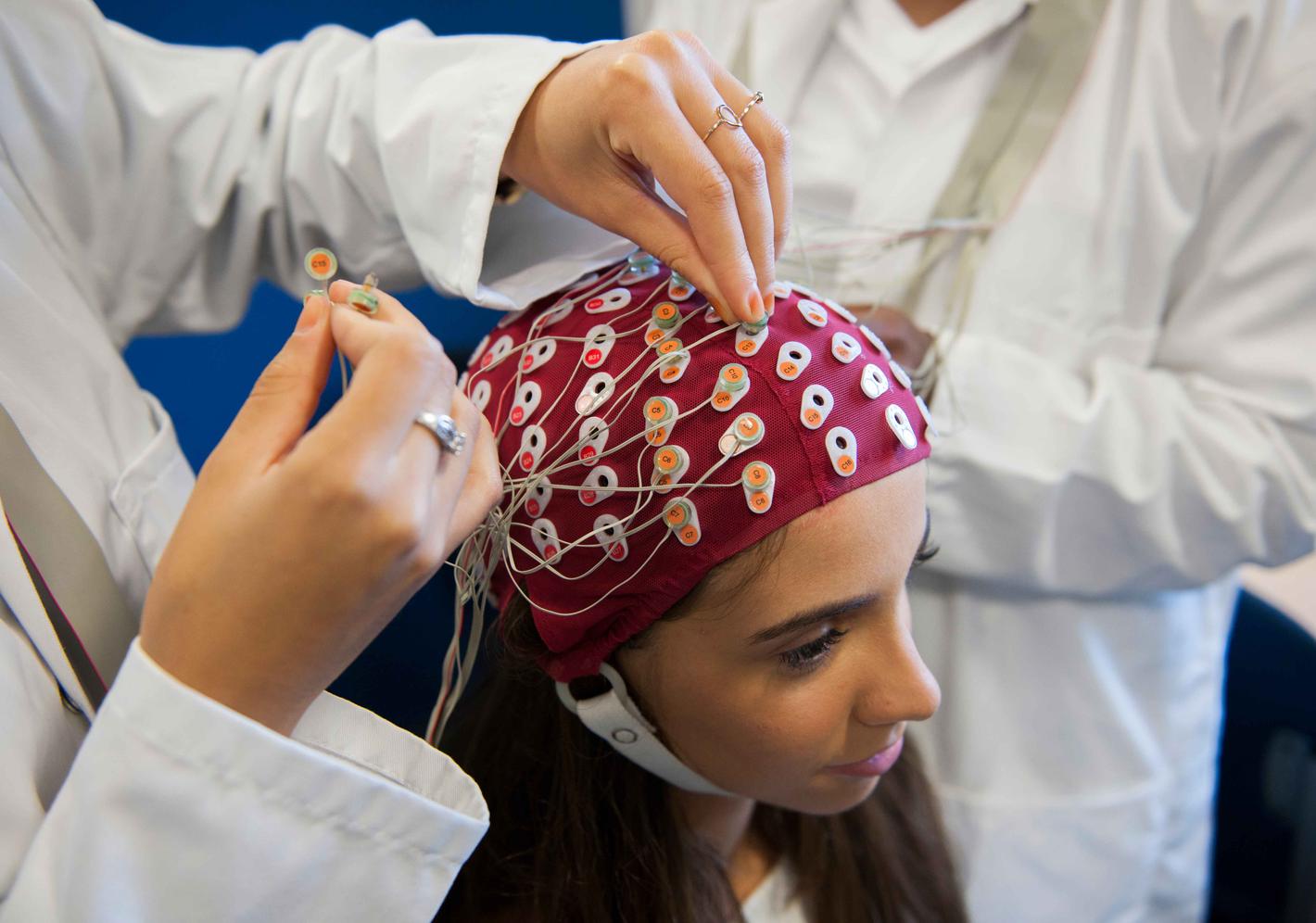 A close up image of a student with a cap on with sensors to detect brain activity