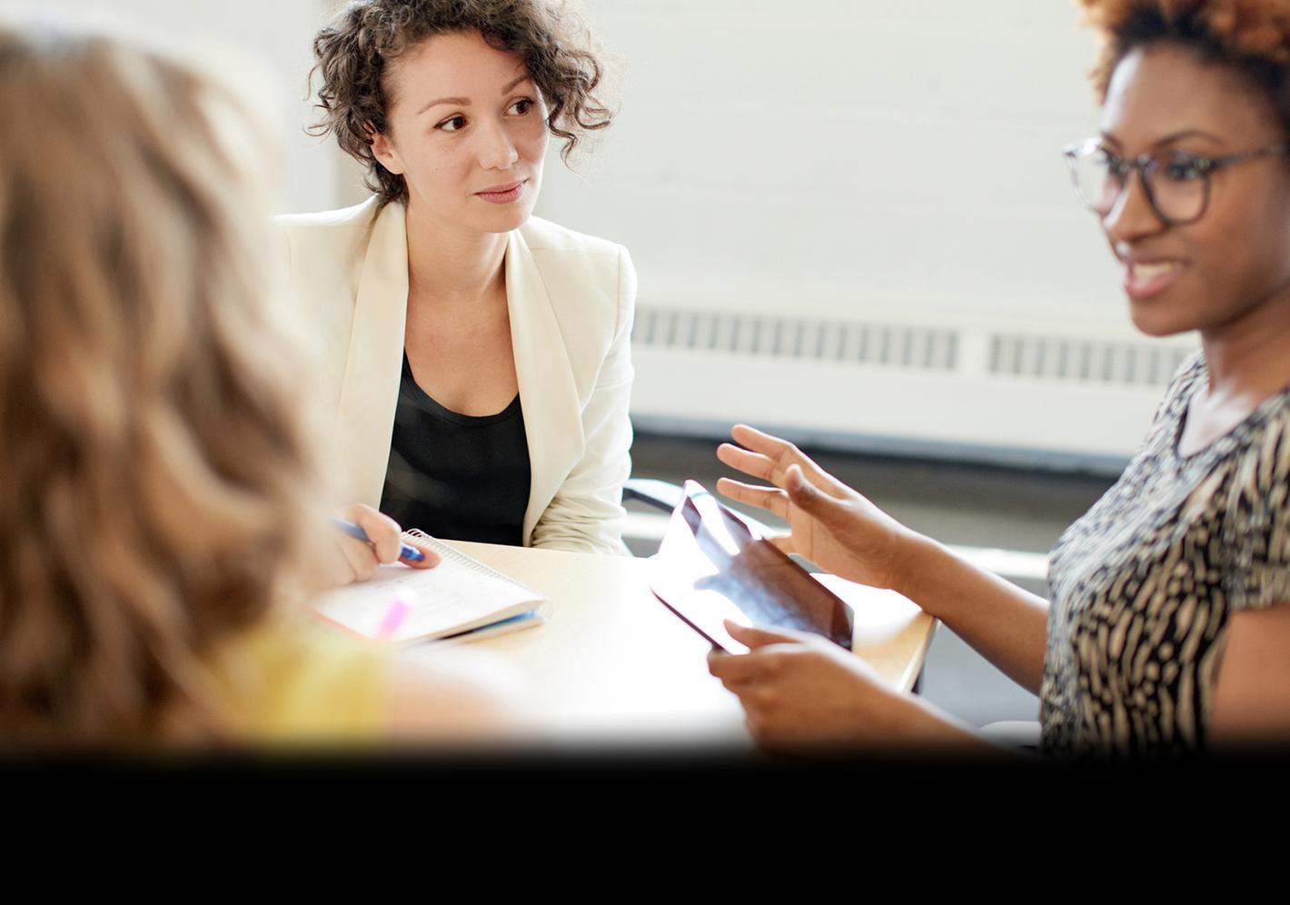 Three women discussing marketing strategies at a conference table.