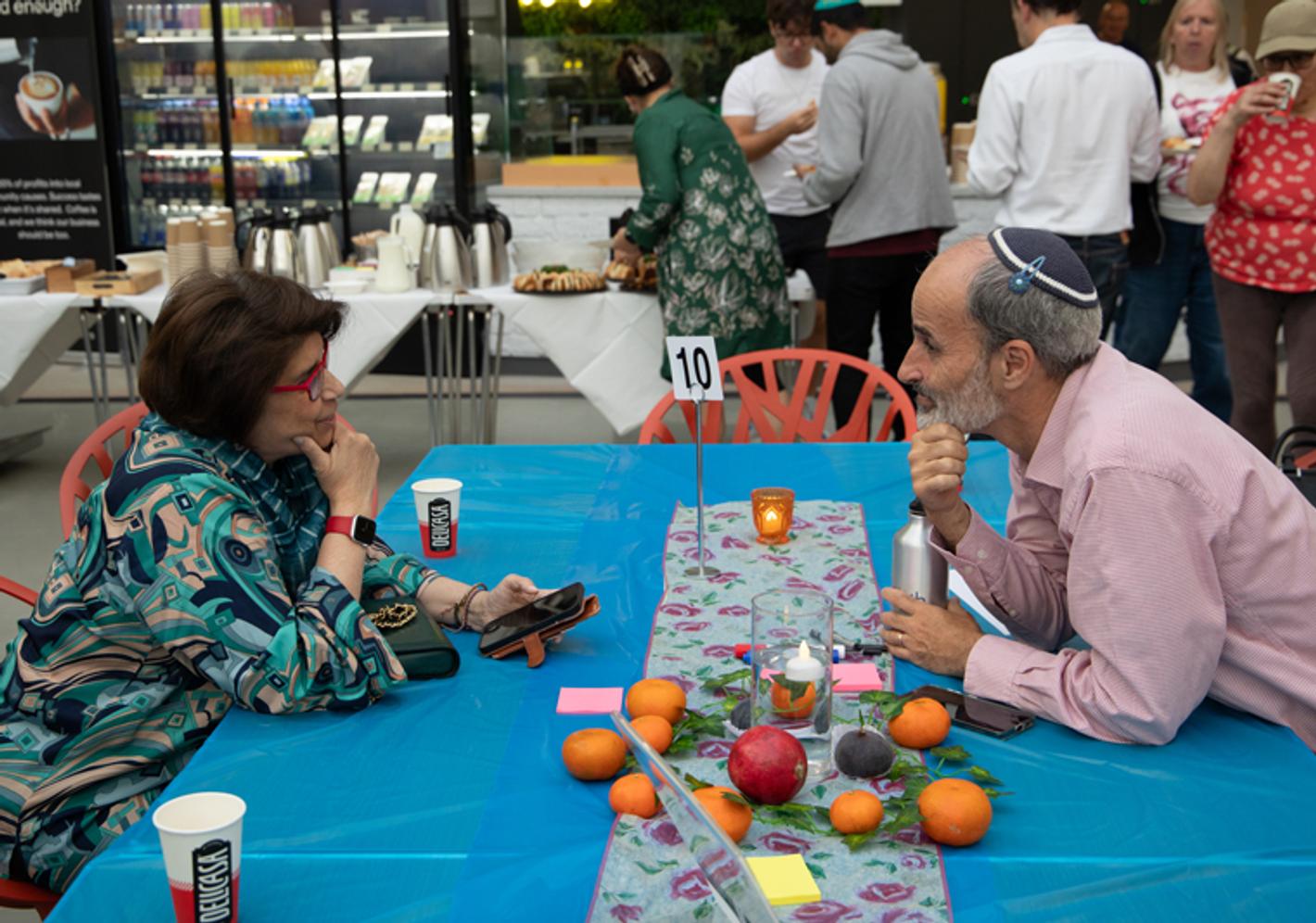 An adult female and an adult male look at each other across a table