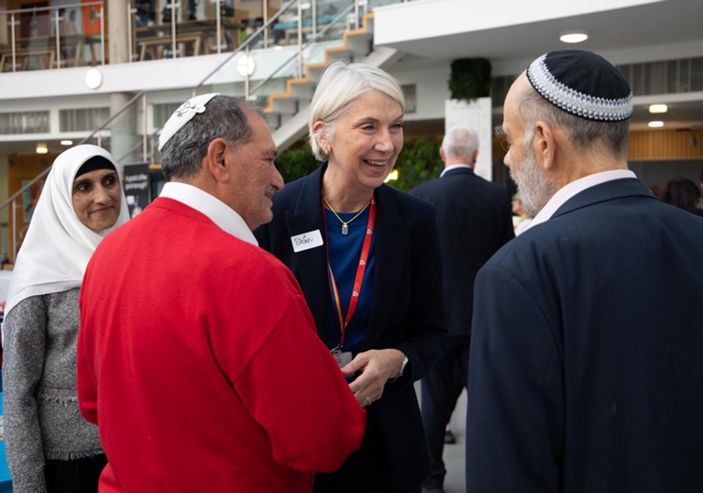 A woman and two Jewish men meet, smile and shake hands