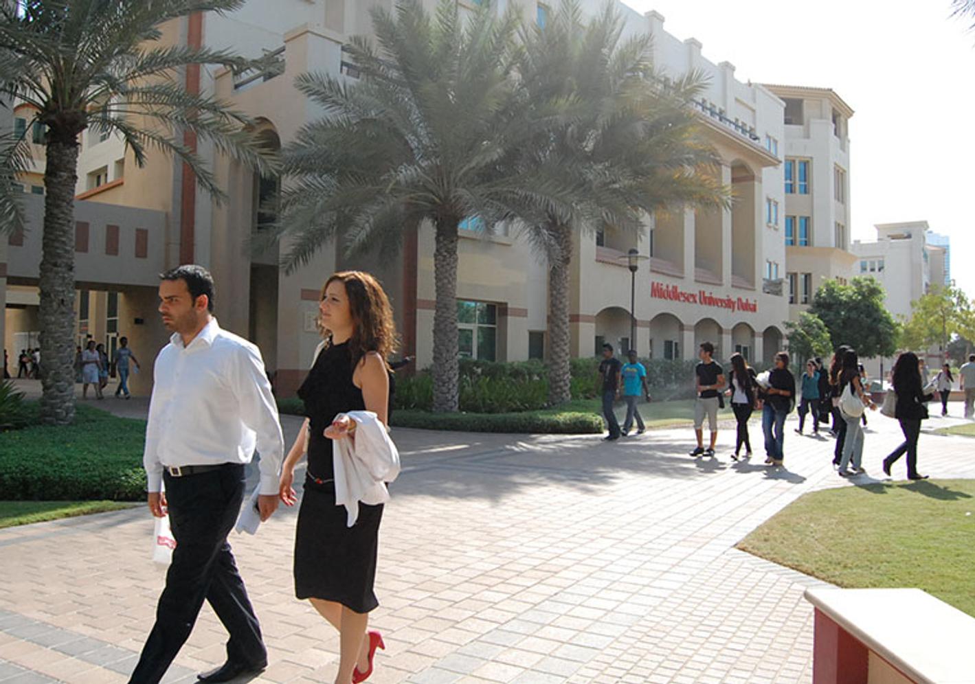 Dubai campus exterior, with palm trees and people