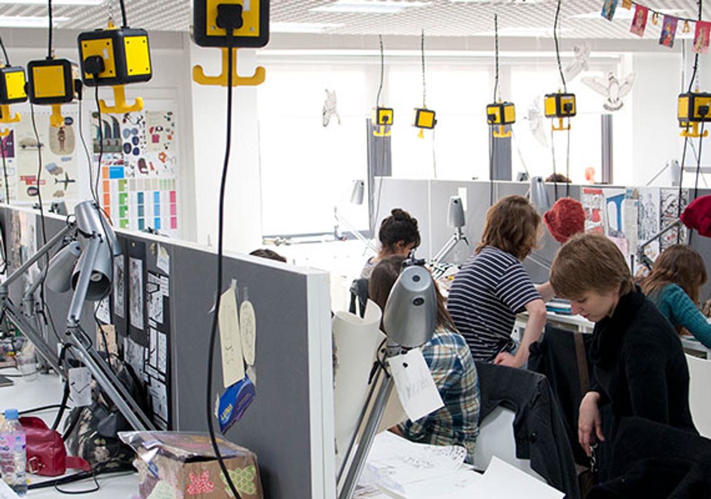 A diverse group of individuals diligently working at desks in an office space, showcasing the professional atmosphere of fine art facilities.