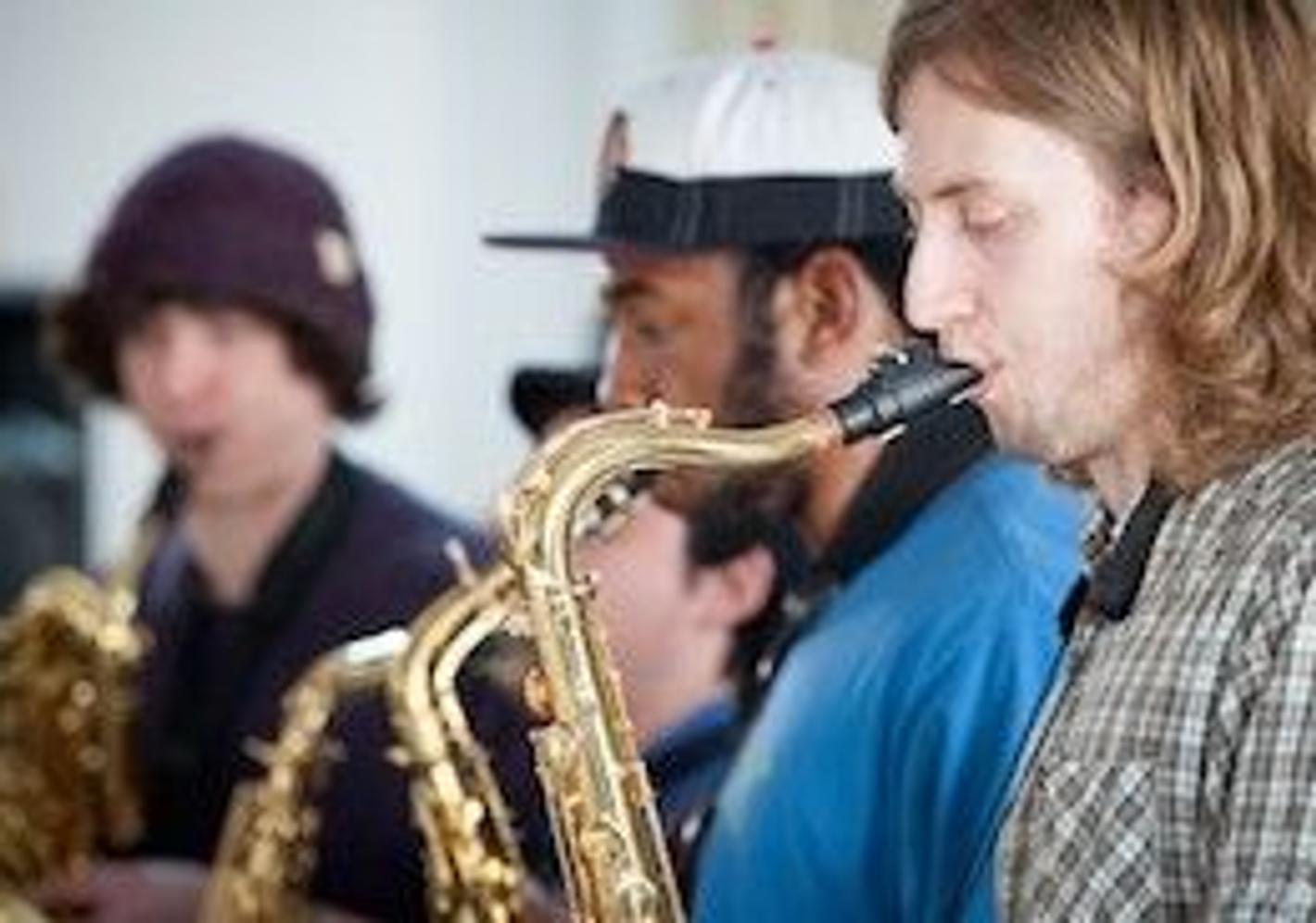 A group of people playing saxophones in a room, showcasing their musical talents and passion for jazz.
