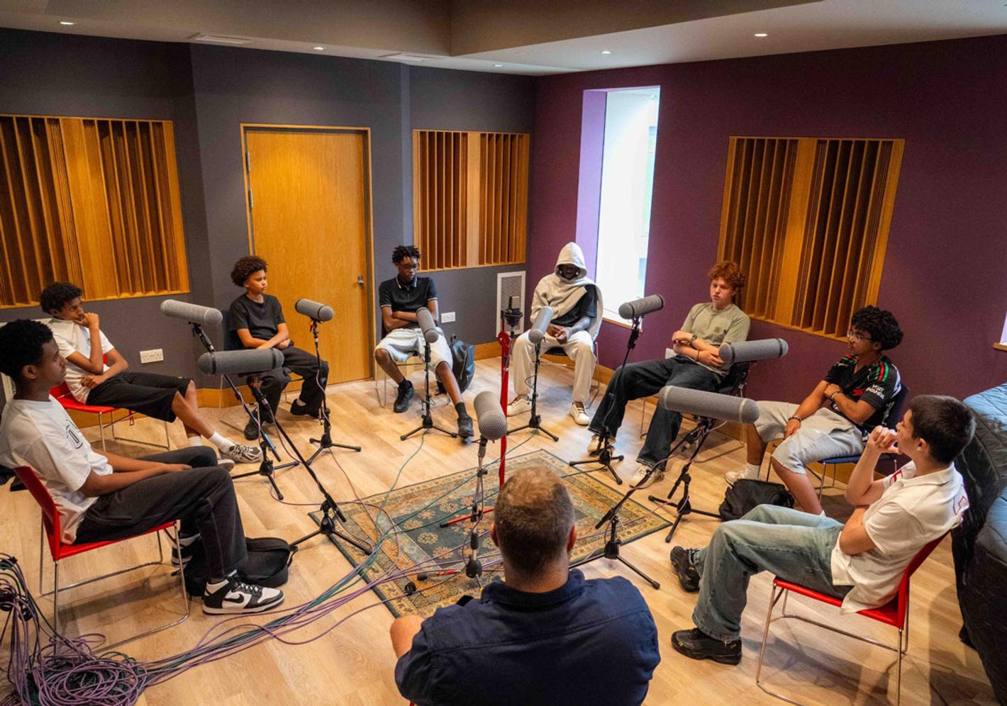 A group of male teenage students record a podcast as part of a project