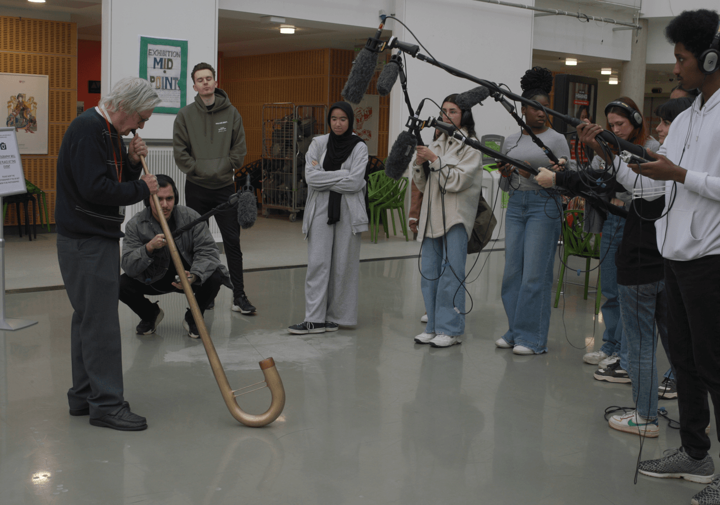 Peter Holmes playing a blowing instrument, being recorded by a film crew