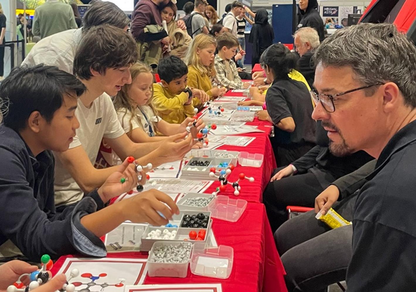 Dirk Wildeboor facilitates the Molymod molecule-building activity at a long table