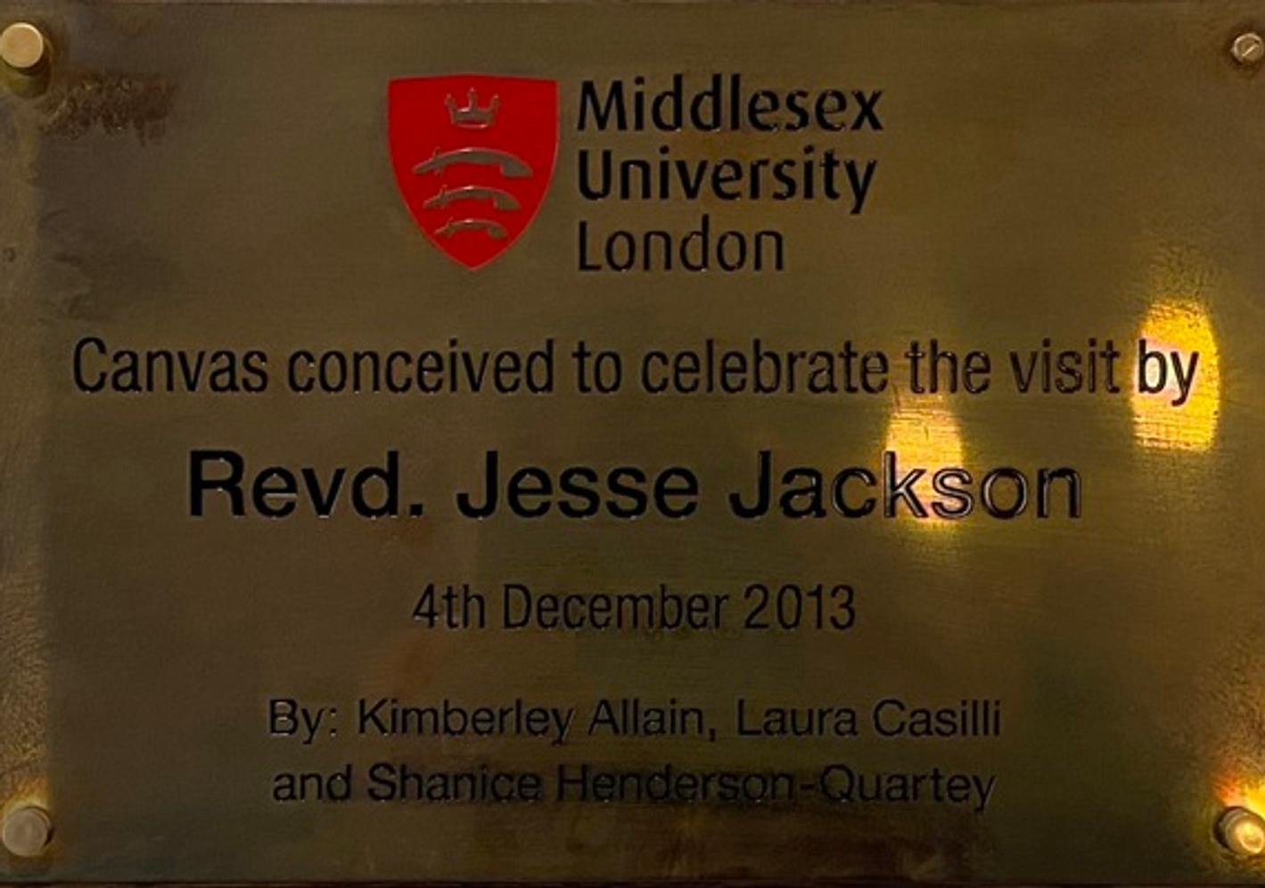 A golden plaque with the Middlesex University London logo. Following text: Canvas conceived to celebrate the visit by Revd. Jesse Jackson, 4th December 2013. By Kimberley Allain, Laura Casilli and Shanice Henderson-Quartey