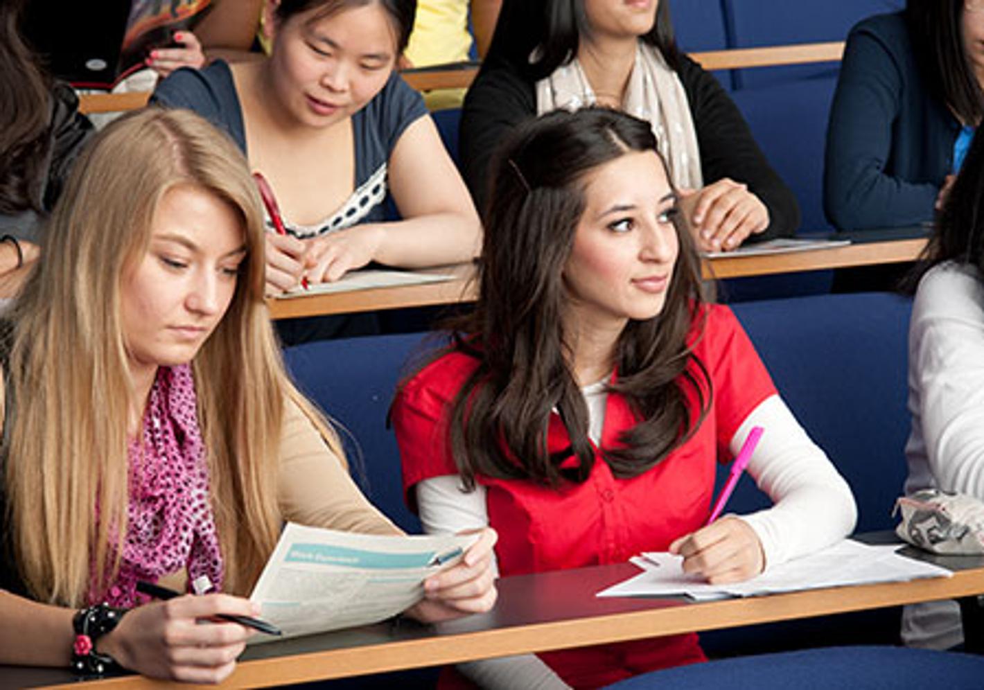 A diverse group of students attentively listening to a lecture in a spacious lecture hall.