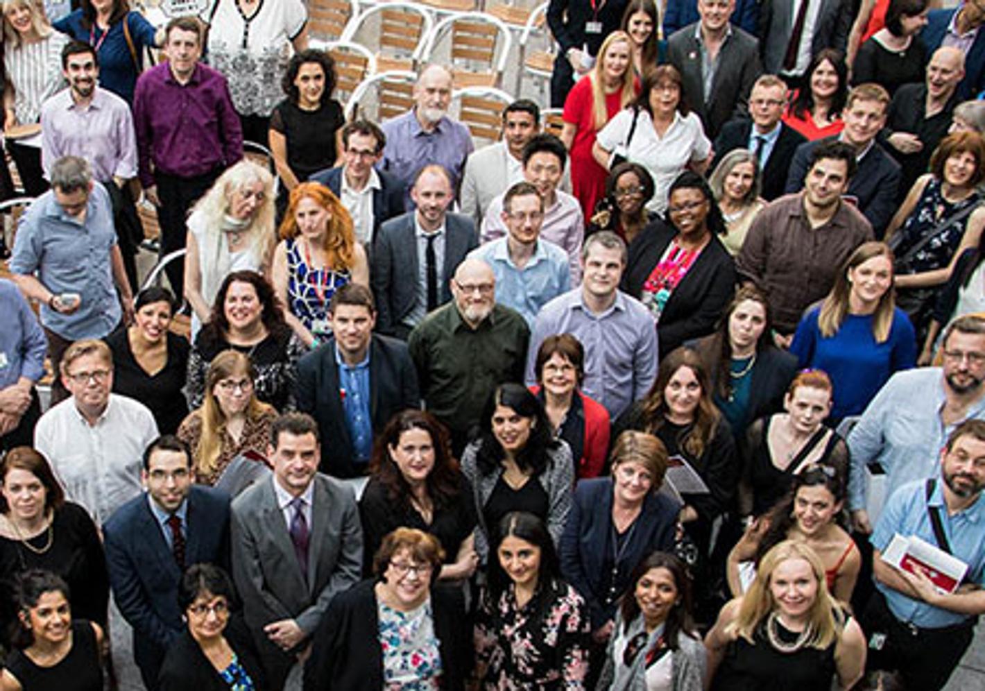 A diverse group of individuals gathered in front of a majestic building, showcasing unity and a sense of togetherness.