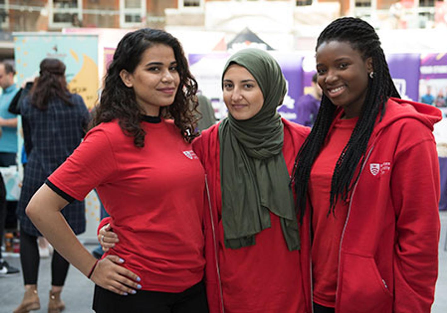 Three students in Middlesex red t-shirts working during an Open Day