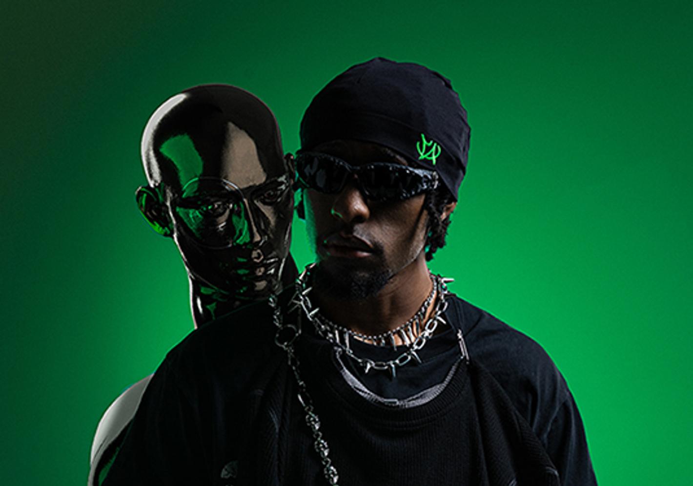 Student posing alongside a robot, with a green screen background