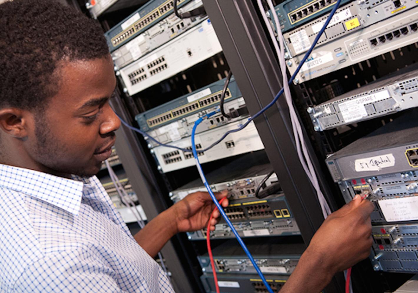 A man diligently working on a server in a data center, ensuring smooth operations and efficient data management.