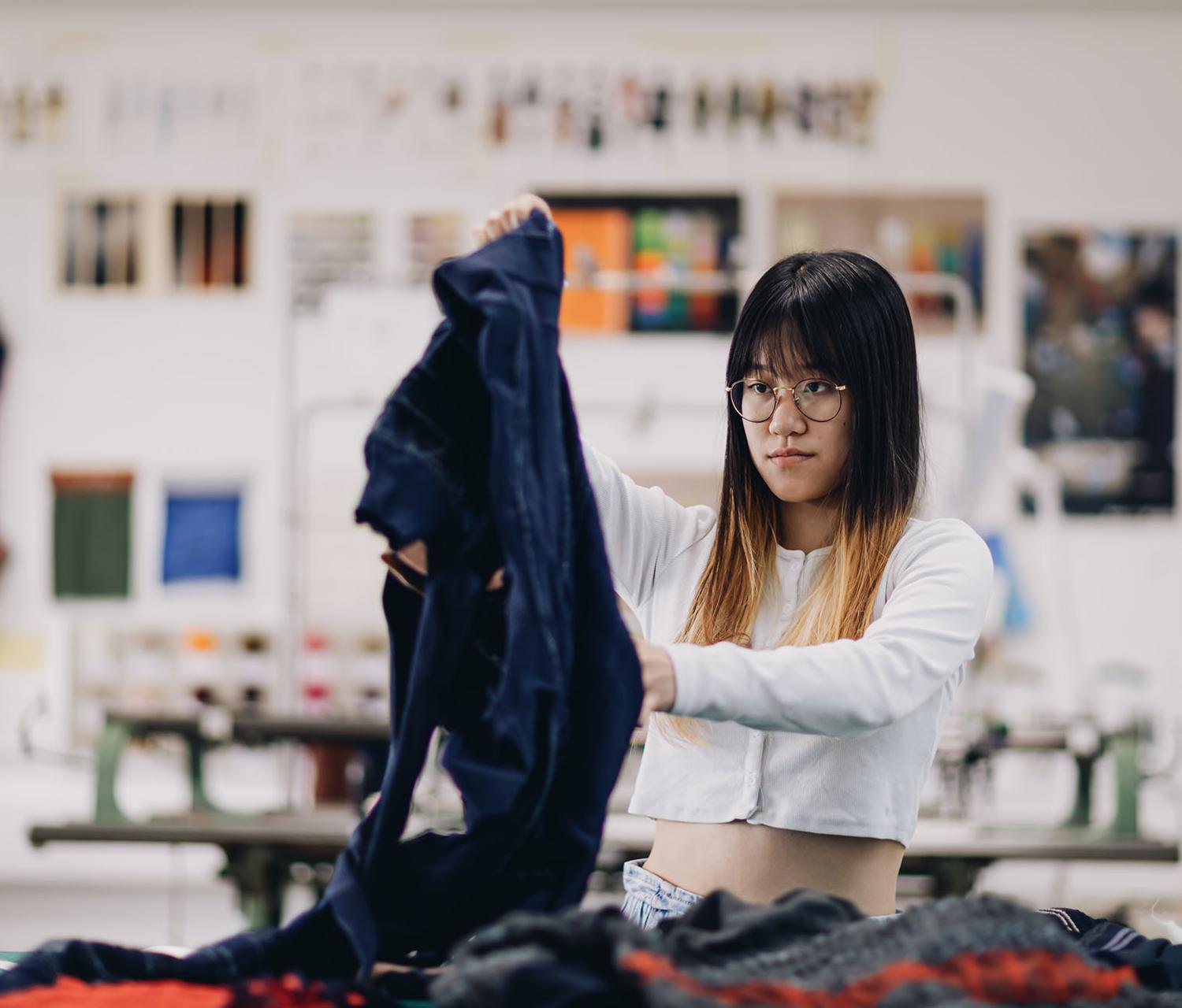 fashion student holding up garment in studio