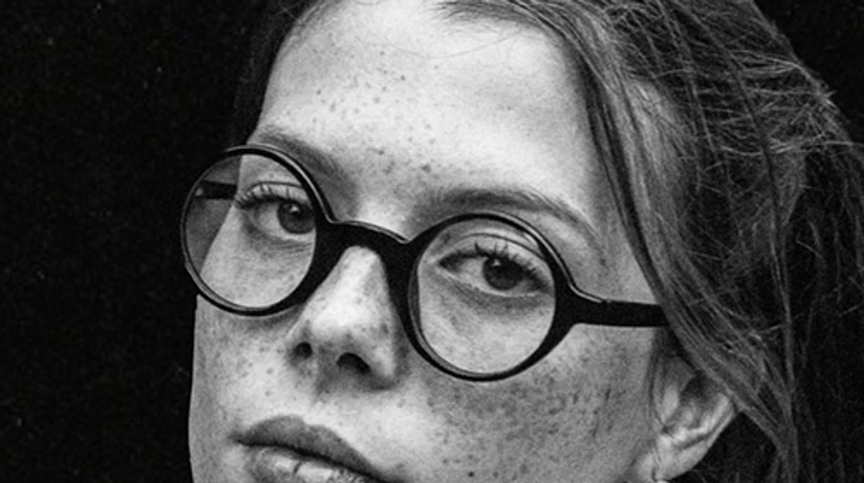 A portrait of a woman wearing glasses, captured in black and white.