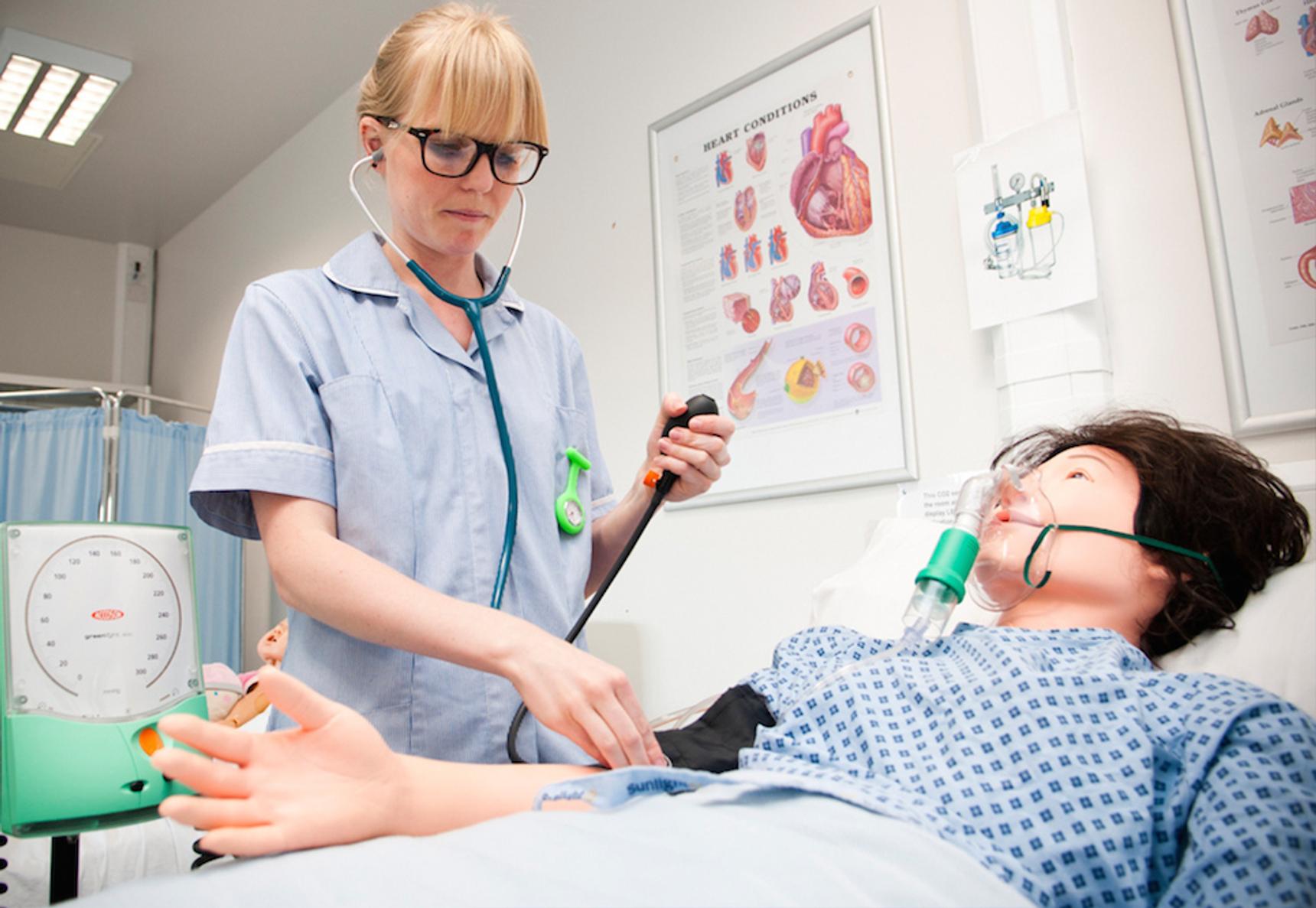 A nursing student checking a dummy's blood pressure