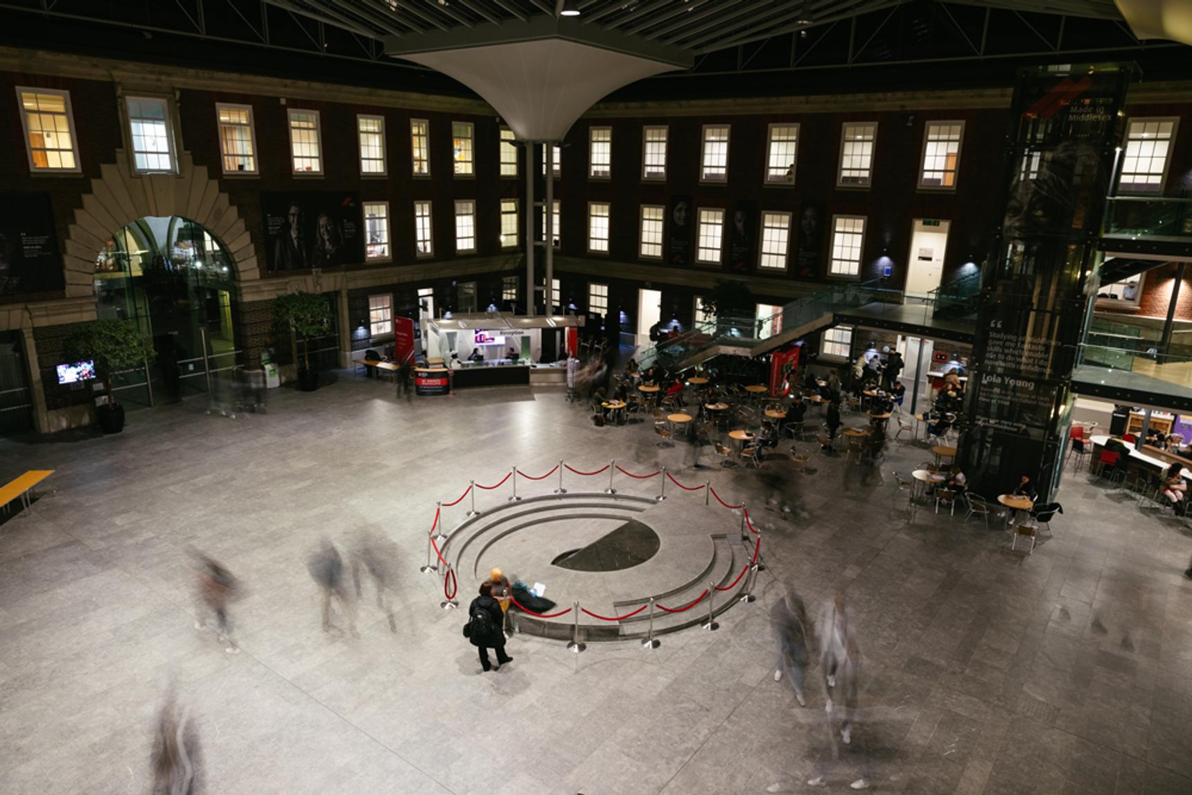 A large interior space in Middlesex University, known as the Quad, seen from a high vantage point at night