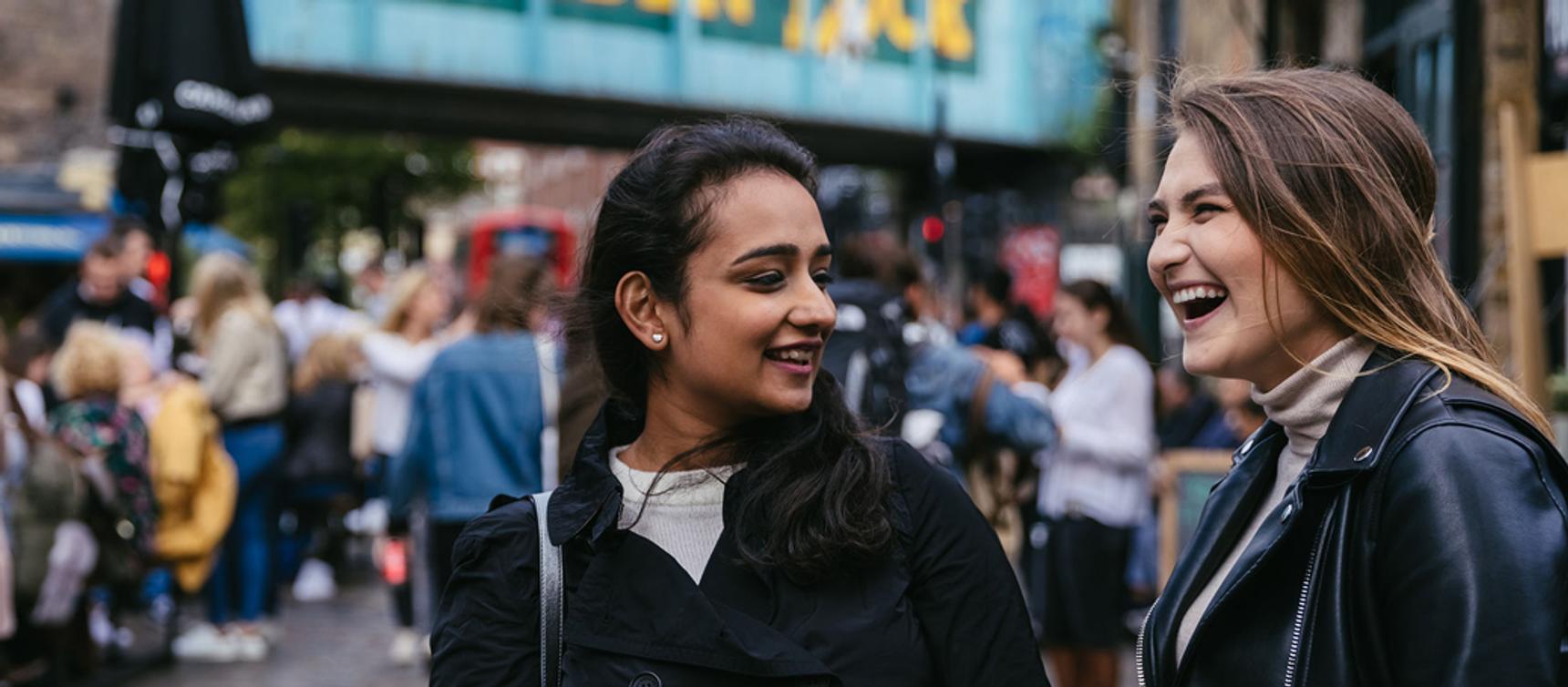 two female students chatting and laughing in Camden Market