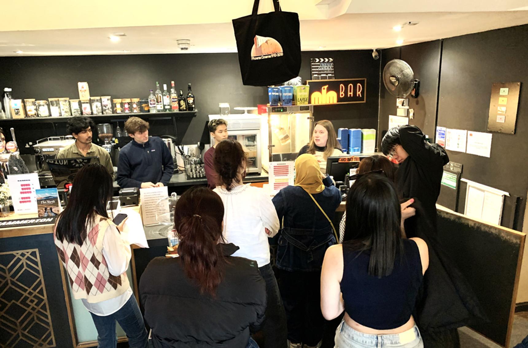 A crowd of people around the front desk of a cinema where refreshments are being sold