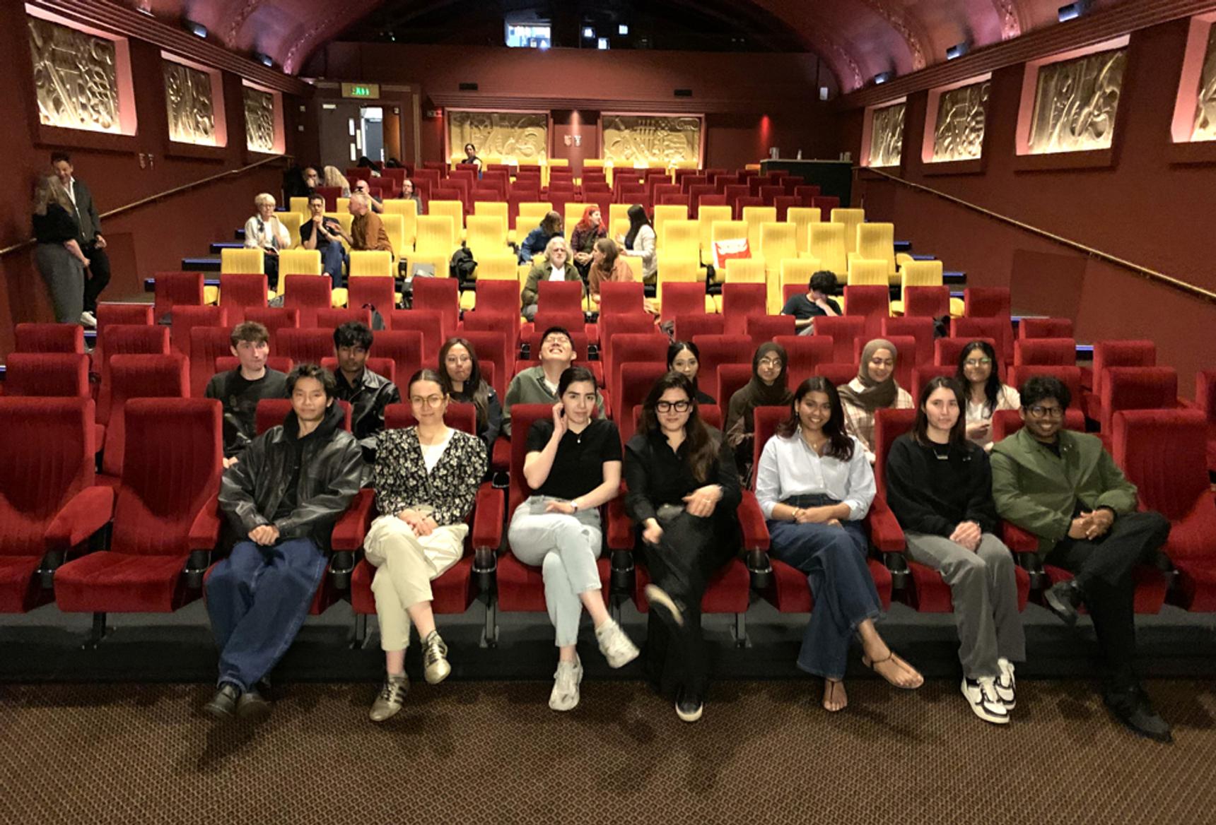A group of people sitting in rows of seats at a cinema